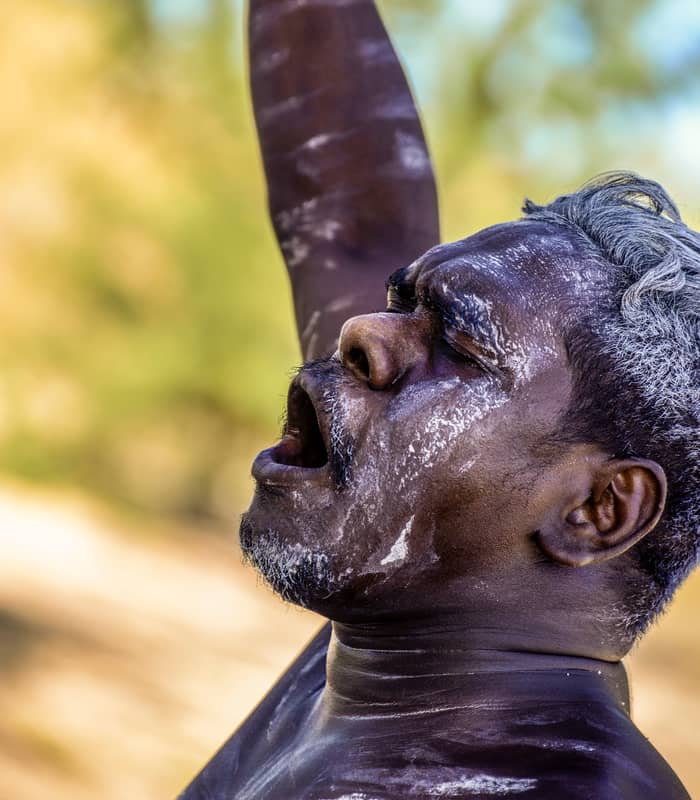An Aboriginal man in traditional white body paint performs a Welcome to Country ceremony in Arnhem Land, Northern Territory, connecting visitors to the ancestral spirit of the land.