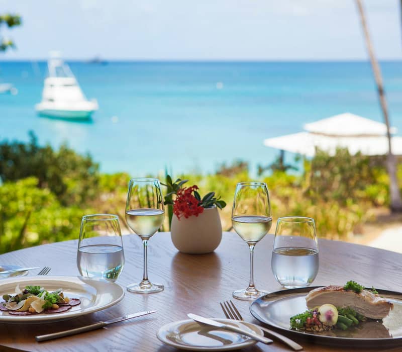 High-angle aerial view of white luxury resort villas along a tropical coastline with clear reef water.